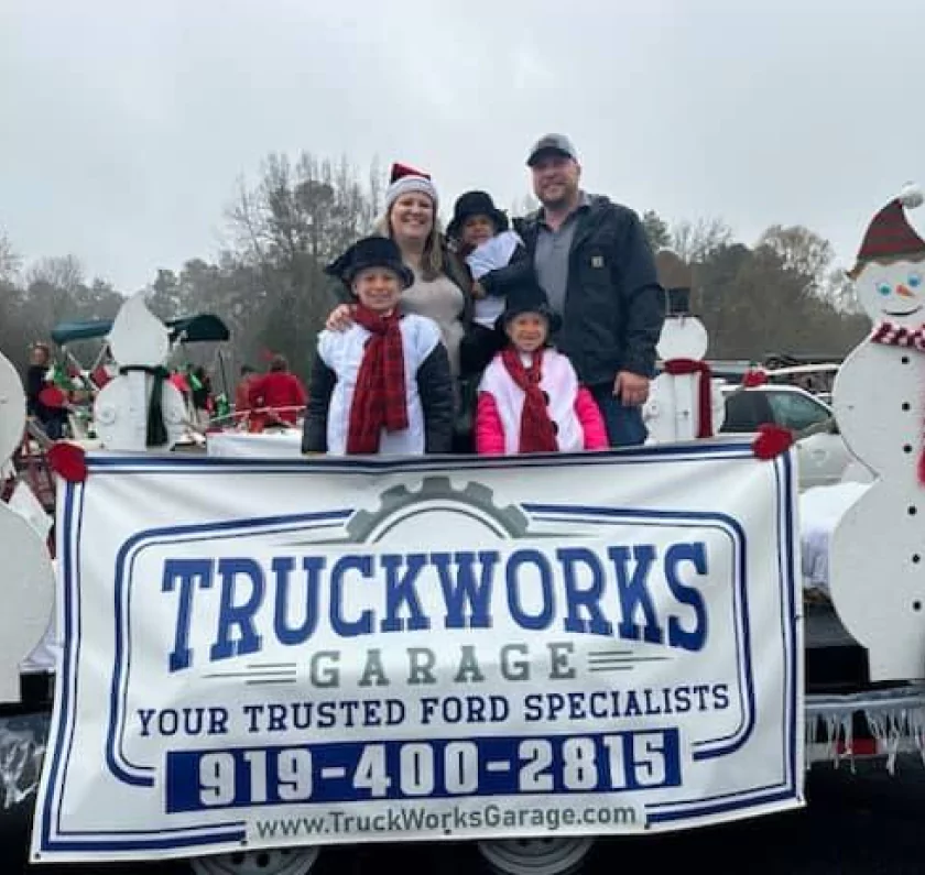 careers, diesel repair in Youngsville, NC at TruckWorks Garage. a group of people standing in a parade holding TruckWorks Garage in Youngsville, NC tarp.